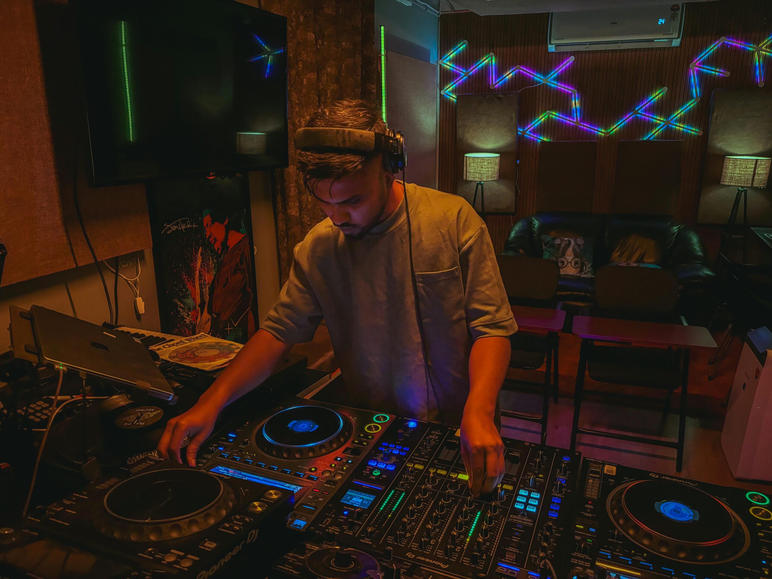 Mobiler DJ für Hochzeiten: Leistungen, Planung, Technik DJ spielt Live-Musik in einem lebendigen Studio mit Neonlichtern und professioneller Ausrüstung.